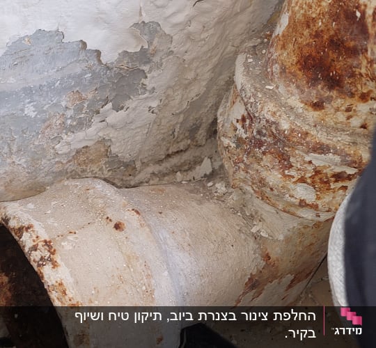 צינור חלוד עם קיר מתקלף ברקע